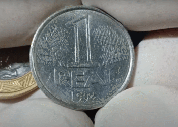 Moeda de 1 real de 1994 sendo segurada com luvas brancas