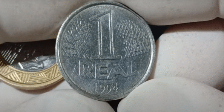Moeda de 1 real de 1994 sendo segurada com luvas brancas